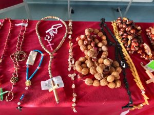 Zdjęcie rozłożonych na stole przykrytym czerwonym materiałem różańców zgłoszonych do konkursu.