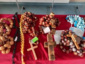 Zdjęcie rozłożonych na stole przykrytym czerwonym materiałem różańców zgłoszonych do konkursu.