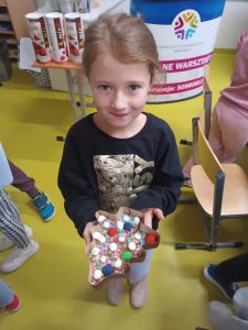 Uczennica klasy pierwszej pokazuje przygotowaną przez siebie czekoladę w foremce w kształcie choinki.