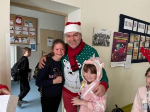 Radny z gminy pozuje do wspólnego zdjęcia z dwoma uczennicami, które obejmuje, Wszyscy szeroko się uśmiechają.