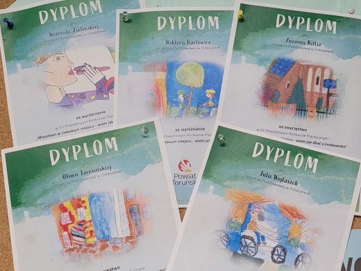 Zdjęcie rozłożonych pięciu dyplomów, które zdobyły uczennice naszej szkoły. Po środku każdego dyplomu zamieszczona jest grafika pracy, którąą wykonała dana uczennica.