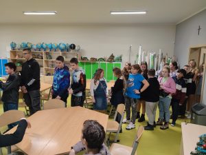 Uczniowie stoją w kolejce w jednej ze szkolnych klas.