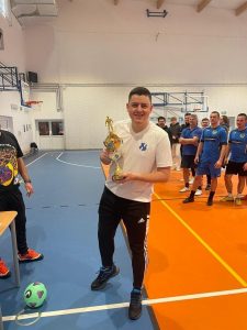 Zdjęcie zawodnika pozującego do zdjęcia z otrzymanym pucharem.