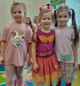 Trzy dziewczynki z oddziału przedszkolnego pozują do wspólnego zdjęcia. Dziewczynki się uśmiechają.
