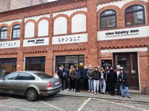 Uczniowie klasy siódmej pozują do wspólnego zdjęcia przed "Niewidzialnym domem" w Toruniu.