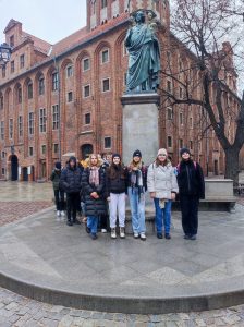 Uczniowie klasy siódmej pozują do wspólnego zdjęcia przed pomnikiem Mikołaja Kopernika w Toruniu.