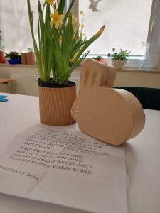 Zdjęcie kwiatka i figurki zajączka przed którymi leży kartka z instrukcją dla uczniów.