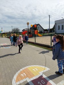 Uczennica klasy drugiej przeskakuje przez długą skakankę, kręconą przez jej koleżanki.