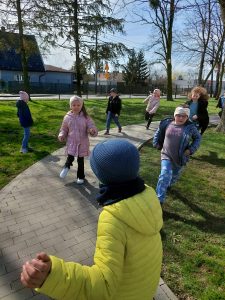 Uczniowie klasy drugiej biegają na terenie przy szkole.