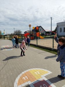 Uczennica klasy drugiej przeskakuje przez długą skakankę, kręconą przez jej koleżanki.