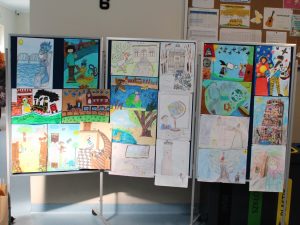 Zdjęcie stojącej tablicy z przyczepionymi pracami nadesłanymi na konkurs.