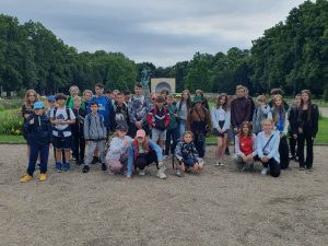 Uczniowie biorący udział w wycieczce pozują do wspólnego zdjęcia na tle parku .