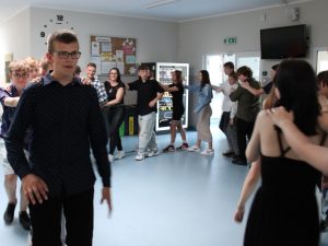 Uczniowie tańczą w wężu na szkolnym korytarzu.