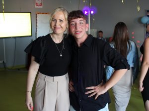 Uczeń pozuje wraz ze swoją wychowawczynią do wspólnego zdjęcia. Oboje szeroko się uśmiechają.