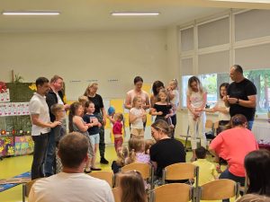 Uczniowie wraz ze swoimi rodzicami stoją po środku sali.