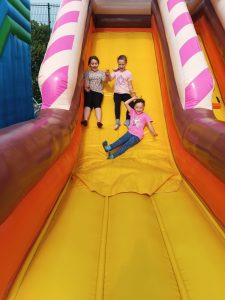 Trzy uczennice trzymają się za ręce podczas zjazdu z dmuchańca.