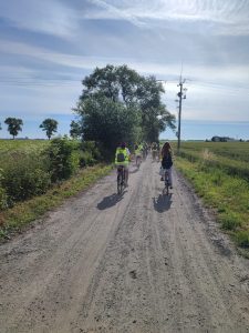 Uczniowie jadą rowerami polną drogą w dwóch rzędach.