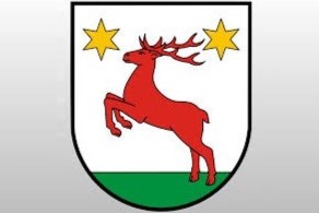 logo gminy Łysomice przestawiające czerwonego jelenia z uniesionymi w górę przednimi łapami. Obok jego rogów po obu stronach umieszczone są żółte gwiazdki.