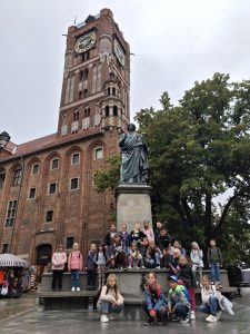 Uczniowie klasy 2 i 3 pozują do wspólnego zdjęcia przy pomniku Mikołaja Kopernika w Toruniu.
