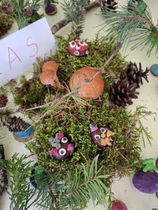 Zdjęcie przygotowanych przez uczniów dekoracji z darów jesieni łączonych ze sobą za pomocą plasteliny. Pomiędzy gałązkami widoczna jest biała kartka z odręcznym napisem "LAS".
