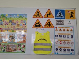 Zdjęcie tablicy magnetycznej, na której umieszczono znaki drogowe, kamizelkę odblaskową oraz grafiki ulic.