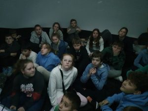 Uczniowie siedzą w kopule. Dzieci patrzą w górę.