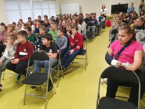 Uczniowie siedzą na krzesłach na sali gimnastycznej podczas prelekcji dotyczącej uzależnienia od nikotyny.