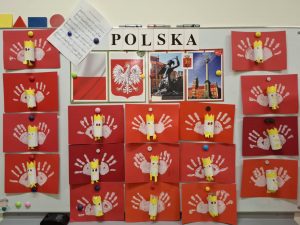 Na białej tablicy po środku umieszczony jest napis "POLSKA" oraz poniżej zdjęcia : polskiej flagi, godła, syrenki warszawskiej i wysokiego pomnika. Wokół umieszczone są prace uczniów przedstawiające godło polski.