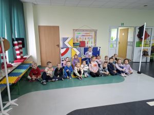 Uczniowie oddziału przedszkolnego siedzą na podłodze w sali toruńskiego oddziału WORD. Dzieci patrzą przed siebie.