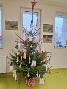 Zdjęcie choinki ozdobionej wykonanymi przez uczniów bombkami z włóczki.