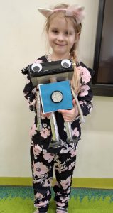 Uczennica oddziału przedszkolnego pozuje do zdjęcia trzymając przed sobą figurkę robota wykonaną na konkurs.