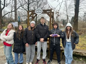 Sześcioro uczniów naszej szkoły biorących udział w wyjeździe pozuje do wspólnego zdjęcia na tle drzew i pergoli na szczycie, której przyczepiony jest napis "POZDROWIENIA Z RÓŻANKI".