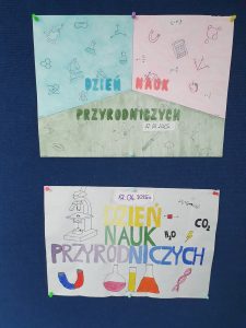 Dwa plakaty promujące dzień nauk przyrodniczych umieszczone są pod sobą na niebieskim tle. Górny plakat wykonany jest w trzech kolorach, niebieskim zielonym i różowym symbolizujących trzy nauki przyrodnicze: chemię, fizykę i biologię. Na każdym tle widoczne są ryciny grafik związane z daną dziedziną. Po środku widnieje wykonany w trzech kolorach napis: "DZIEŃ NAUK PRZYRODNICZYCH" a pod nim data 12.06.2025. Dolny plakat przedstawia grafiki związane z naukami przyrodniczymi. Po środku widnieje kolorowy napis: "DZIEŃ NAUK PRZYRODNICZYCH" a nad nim odręcznie napisana data 12.06.2025.