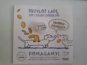 Ulotka promująca akcję "Psia lekcja". U góry napis "PRZŁÓŻ ŁAPĘ DO CZEGOŚ DOBREGO!" a pod nim grafika dwóch jamników zwróconych do siebie pyszczkami i złączonych chmurką z napisem "ZBIÓRKA PIENIĘDZY". Do brzucha jednego jamnika wlatują złote monety jak do skarbonki, a drugi z jamników trzyma monetę w pysku. Pod spodem napis: "POMAGAMY! Zbieramy pieniądze w ramach programu PSIA LEKCJA na dogoterapię dzieci w szpitalach.". Po lewej stronie logo programu psia lekcja a po prawej stowarzyszenia zwierzęta ludziom.