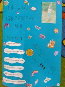 Plakat na niebieskiej kartce ozdobiony kolorowymi naklejkami (kwiaty, tęcza, okulary, zwierzątka, aparat fotograficzny). U góry napis: „Oliwia Owczarczyk kl. II”, obok znajduje się zdjęcie dziewczynki w różowej bluzce i dżinsach. Po lewej stronie tytuł „Moje pomysły:” oraz lista w białych chmurkach: Więcej konkursów Więcej imprez np. piżama party Więcej piłek do piłkarzyków Zdrowe śniadanie na trawie Dzień koszulki piłkarskiej Dzień postaci z bajek lub filmów Po prawej stronie duży napis: „Proszę o Twój głos!!!”.