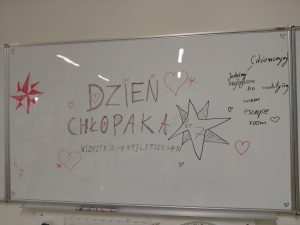 Tablica suchościeralna z napisem „Dzień Chłopaka – wszystkiego najlepszego!!!”. Wokół znajdują się narysowane serca, gwiazdy i komentarz: „Dziewczyny! Jesteśmy najlepsze bo zrobiliśmy wam escape room”.