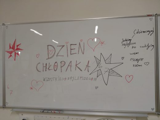 Tablica suchościeralna z napisem „Dzień Chłopaka – wszystkiego najlepszego!!!”. Wokół znajdują się narysowane serca, gwiazdy i komentarz: „Dziewczyny! Jesteśmy najlepsze bo zrobiliśmy wam escape room”.