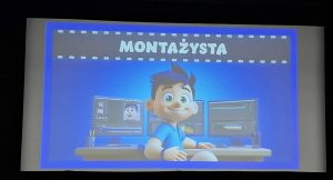 Na ekranie kinowym wyświetlona jest ilustracja postaci pracującej przy dwóch monitorach z programem do montażu filmów. Nad obrazem napis „Montażysta”.