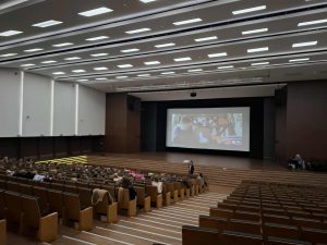 ala kinowa z uczniami klas 0–3 oglądającymi film edukacyjny o zawodach. Na ekranie widać scenę z filmu, a dzieci siedzą w kilku rzędach foteli.