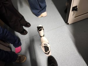 Kilka butów ustawionych jeden za drugim w kierunku drzwi podczas andrzejkowej zabawy.