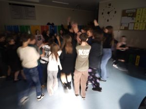 Uczniowie tańczą w grupie na szkolnym korytarzu podczas dyskoteki andrzejkowej.