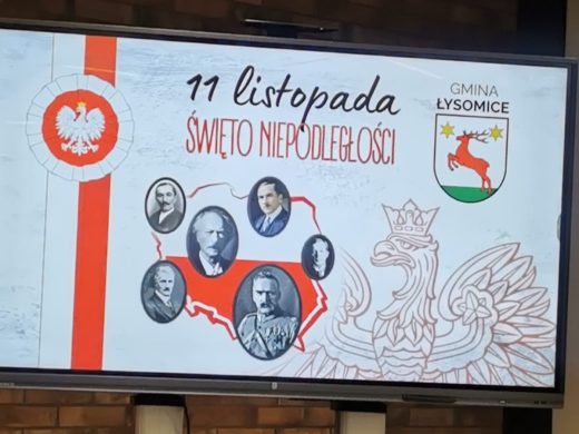 Plansza z okazji 11 listopada – Święta Niepodległości. Po lewej stronie widnieje biało-czerwona kokarda narodowa z godłem Polski. Na środku znajduje się kontur mapy Polski z pięcioma owalnymi portretami historycznych postaci. Po prawej stronie umieszczono herb gminy Łysomice oraz zarys stylizowanego orła.