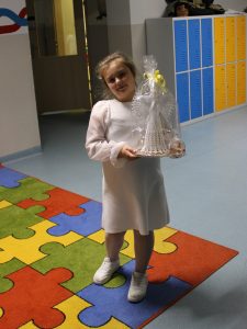 Dziecko trzyma zapakowaną figurkę anioła zakupioną na szkolnym kiermaszu bożonarodzeniowym.