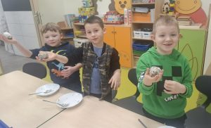 Trzech uczniów trzyma w dłoniach gotowe kule z ziaren i smalcu – ekologiczne karmniki dla ptaków.