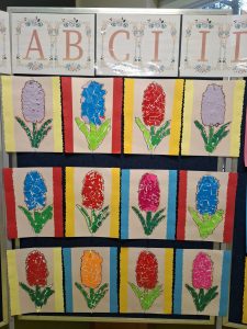 Wystawa prac plastycznych dzieci – kolorowe hiacynty wykonane techniką wydzieranki, umieszczone pod napisem z liter alfabetu.