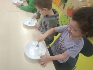 Dzieci z oddziału przedszkolnego rozgniatają w miseczkach smalec widelcem.