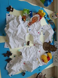 Fragment makiety przedstawiającej obszar polarny z papierowym lodem, zwierzętami z plasteliny i kolorowymi klockami.