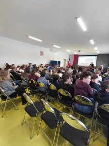 Widok sali z dużą grupą uczniów uczestniczących w prelekcji na temat zdrowego odżywiania i napojów energetycznych.