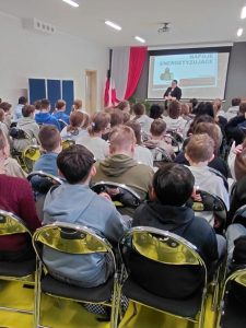 Uczniowie klas IV–VIII siedzący na krzesłach w sali szkolnej podczas spotkania edukacyjnego prowadzonego przez przedstawicielkę sanepidu.