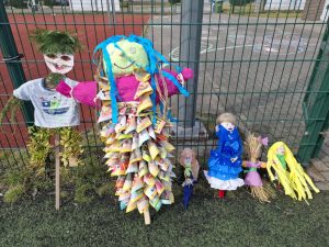 Kolorowe kukły symbolizujące zimę wykonane przez dzieci stoją przy ogrodzeniu na terenie szkoły.